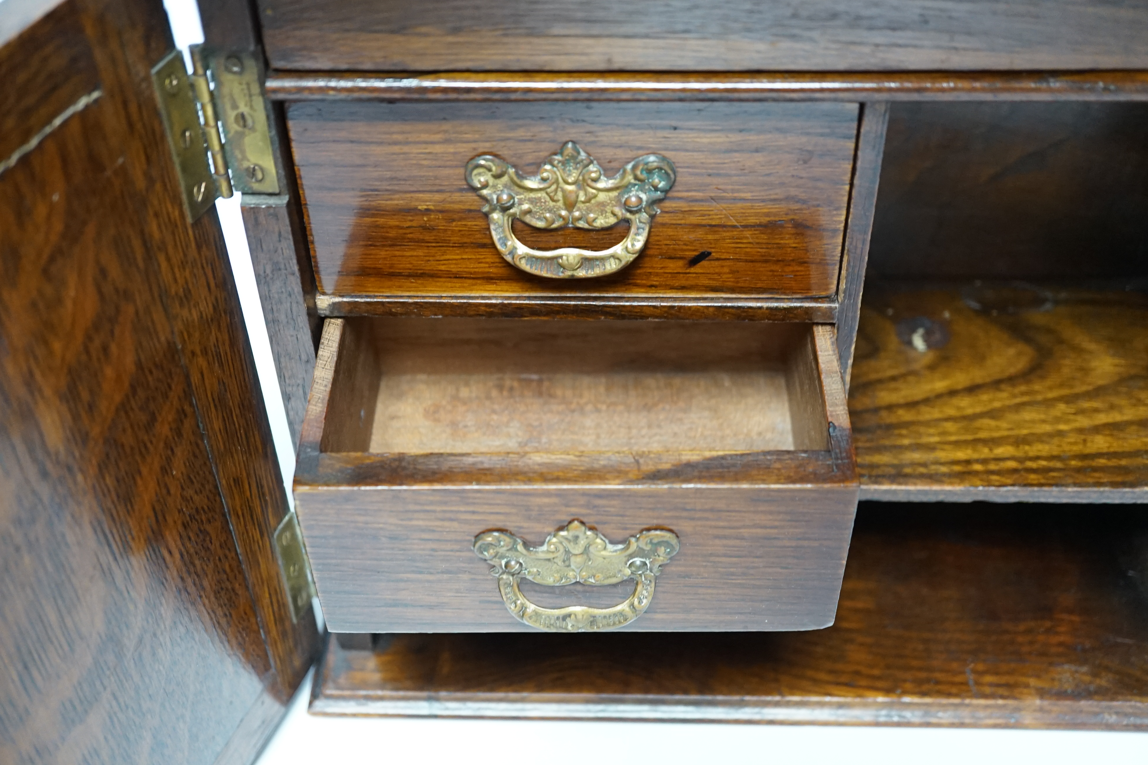 A carved oak smoker's compendium and accessories including cased cheroot holders, 25cm high